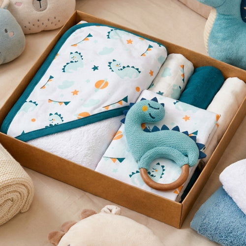 Baby care products including towels, a blanket, and a teething ring in a box on a beige couch.